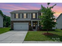 Charming two-story home featuring stone accents, a two-car garage, and a manicured front lawn at 711 Saddlebred Ln, Locust, NC 28097
