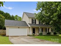 Charming two-story home with a well-maintained lawn and a two-car garage on a sunny day at 8808 Palmutum Pl, Charlotte, NC 28269