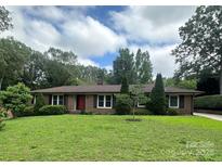 Charming brick home with a well-manicured lawn and mature trees on a partially cloudy day at 1115 Dumbarton Rd, Gastonia, NC 28054