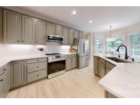 Modern kitchen with stainless steel appliances, light countertops, and light wooden floors at 118 Tayport Dr, Troutman, NC 28166