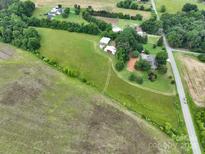 Expansive aerial view featuring farmland, trees, outbuildings and a two-story home near a road at 13101 Pine Bluff Rd, Midland, NC 28107