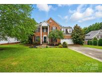 Charming two-story brick home with a lush green lawn, mature trees, and a well-maintained landscape at 14616 Pomerol Ln, Pineville, NC 28134