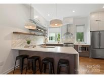 This modern kitchen features a marble backsplash, stainless steel appliances, a breakfast bar and modern pendant lighting at 2653 Shenandoah Ave, Charlotte, NC 28205