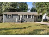 Charming single-story home with a gray brick exterior, a well-maintained lawn, and a carport at 2701 Ravencroft Dr, Charlotte, NC 28208