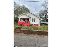 Charming home featuring a covered front porch, vibrant red foundation, and a detached carport at 325 N Caldwell Ave, Newton, NC 28658