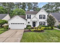 Charming two-story home featuring a landscaped front yard, attached garage, and classic white siding with black shutters at 4407 Beauvista Dr, Charlotte, NC 28269