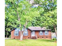 Charming brick home with a well-manicured lawn and mature trees, offering shade and curb appeal at 7133 Tall Tree Ln, Charlotte, NC 28214