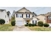 Charming two-story home featuring light yellow siding, a garage, and well-maintained front yard landscaping at 8139 Deodora Cedar Ln, Charlotte, NC 28215