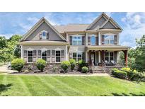 Beautiful two-story home boasts impeccable landscaping and a welcoming front porch at 9011 Kensington Forest Dr, Harrisburg, NC 28075