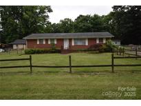 Charming one-story brick home with a well-manicured front yard and a rustic wooden fence at 908 Ravendale Dr, Charlotte, NC 28216