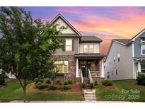 Charming two-story home featuring brick accents, neutral siding, well-manicured landscaping, and a welcoming front porch at 915 Claires Creek Ln, Davidson, NC 28036
