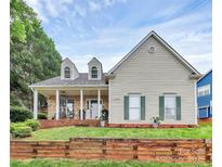 Charming two-story home featuring a stone porch, dormer windows, green shutters, and a beautifully landscaped front yard at 10449 Quiet Bay Ct, Charlotte, NC 28278