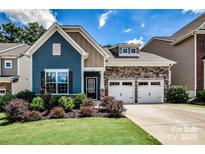 Charming two-story home boasts blue siding, stone accents, and a two-car garage on a well-manicured lawn at 130 Swamp Rose Dr, Mooresville, NC 28117