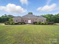Charming brick home featuring a meticulously landscaped front yard with lush green grass and manicured bushes at 1340 Canter Ln, York, SC 29745