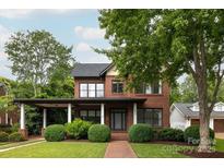Beautiful brick home featuring a landscaped front yard with mature trees and covered entryway at 1833 The Plz, Charlotte, NC 28205