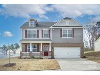 Charming two-story home featuring a covered front porch, brick accents, and a two-car garage at 427 Carolina Hemlock Dr, Locust, NC 28097