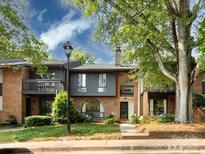Charming townhome with a brick facade, front balcony, mature trees, and well-maintained landscaping at 5809 Sharon Rd # G, Charlotte, NC 28210