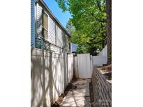 View of the side yard, showing a white fence and a path to a gated entrance and retaining wall at 7107 Stonington Ln, Charlotte, NC 28227