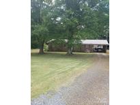 Charming single-story brick home with a metal roof and a covered carport surrounded by mature trees at 10500 Bethel Church Rd, Midland, NC 28107