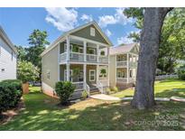 Charming two-story home featuring double porches, classic white railings, and beautiful greenery at 12220 Huntersville Concord Rd, Huntersville, NC 28078
