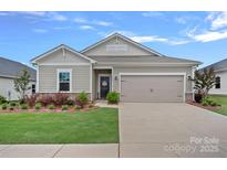 Charming one-story home featuring a well-manicured lawn, a two-car garage, and decorative landscaping at 1344 Sweet Pea St, Monroe, NC 28110