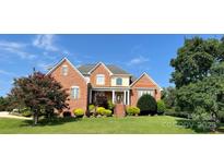 Charming brick home featuring a manicured lawn, mature trees, and inviting front entrance at 140 Hunters Hill Dr, Statesville, NC 28677