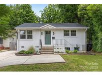 Charming white brick home featuring a beautifully landscaped front yard and a welcoming green front door at 1713 Shamrock Dr, Charlotte, NC 28205