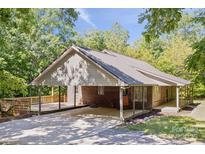 Charming brick home featuring a metal roof, covered carport and a spacious wooden deck surrounded by lush greenery at 3090 Goblet Rd, Richburg, SC 29729