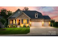 Charming brick home featuring a well-manicured lawn, inviting front porch, and a spacious three-car garage at 7026 Wyngate Pl, Lancaster, SC 29720
