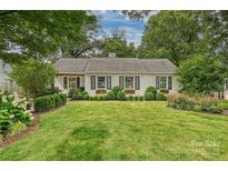 Charming one-story white brick home with black shutters and beautifully manicured landscaping at 829 Sedgefield Rd, Charlotte, NC 28209