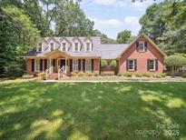 Charming brick home featuring a well-manicured lawn and dormer windows for added natural light at 1518 Appaloosa Way, Gastonia, NC 28056