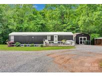 Charming home with a wooden deck and a gravel driveway surrounded by lush greenery and a storage shed at 2289 Mccloud St, Denver, NC 28037