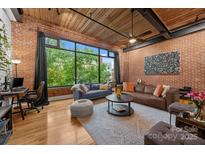 Bright living room with large window, exposed brick, hardwood floors, and modern furnishings at 310 Arlington Ave # 409, Charlotte, NC 28203