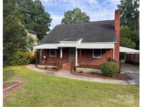 Charming brick home featuring a well-maintained lawn, a chimney, and awning-covered porches at 3726 The Plaza None, Charlotte, NC 28205