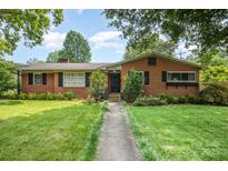 Charming brick home with a well-manicured lawn and mature trees providing shade at 4044 Somerdale Ln, Charlotte, NC 28205