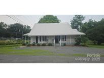 Charming one story home featuring a metal roof, fresh landscaping and rocking chair front porch at 804 N Main St, Oakboro, NC 28129