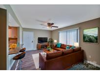 Inviting living room features a brown leather couch and a mounted TV at 809 High Meadow Ln # F, Charlotte, NC 28217