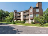 Attractive condo building with multiple balconies, manicured landscaping, and mature trees at 8208 Cedar Glen Dr, Charlotte, NC 28212