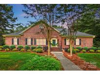 Charming brick home featuring a manicured front lawn, mature trees, and inviting entrance, perfect for a serene suburban lifestyle at 102 Rosewood Ln, Locust, NC 28097