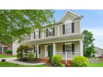 Charming two-story home featuring a welcoming front porch and beautifully landscaped front yard at 10306 Madison Park Dr, Charlotte, NC 28269