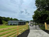 Charming home with a fenced yard and an ornate metal gate, set against a lush green landscape at 117 Autumn Woods Dr, Kings Mountain, NC 28086