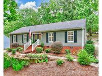 Charming single-story home with a landscaped front yard and classic architectural details including gray siding and black shutters at 1230 Somersby Ln, Matthews, NC 28105