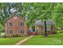 Charming two-story brick home with a well-manicured lawn and mature trees providing shade at 2301 Seth Thomas Rd, Charlotte, NC 28210