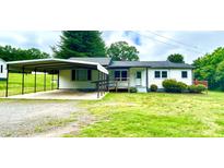 Ranch-style home with white siding, a covered carport, front porch, and mature trees in the front yard at 271 Nc 16 N Hwy, Taylorsville, NC 28681