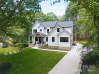 Stunning two-story modern farmhouse with lush front yard and a charming, covered porch at 3601 Woody Grove Ln, Charlotte, NC 28210