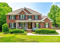 Beautiful two-story brick home with a manicured lawn, covered porch and dark shutters on a sunny day at 4712 Amberside Dr, Rock Hill, SC 29732