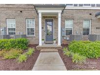 Charming brick townhome with a welcoming front door and beautiful landscaping at 5060 Harrowsmith Ln, Charlotte, NC 28204