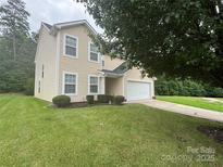 Two-story home with light yellow siding, a front lawn, and a two-car garage at 6229 Sid Crane Dr, Charlotte, NC 28216