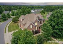 Expansive brick home in mature neighborhood, featuring a manicured lawn and lush trees at 8409 Olde Stonegate Ln, Mint Hill, NC 28227