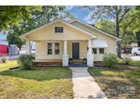 Charming yellow bungalow featuring a covered front porch, landscaped yard, and inviting curb appeal at 1112 Concord Ave, Monroe, NC 28110